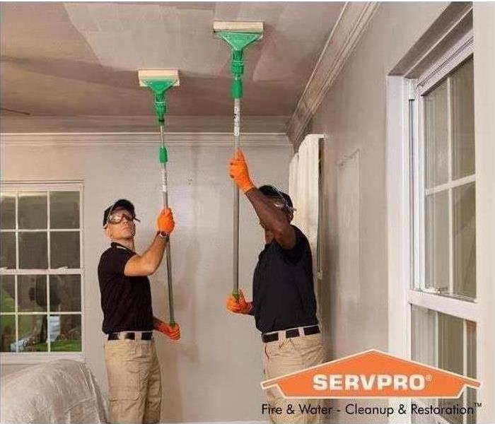 Two Servpro employees clean soot from ceiling 